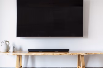 Wandmontierter Flachbildfernseher über einem Konsolenmöbel in einem minimalistischen Wohnzimmer als Sinnbild für ein modernes Heimkino-Setup mit Soundbar